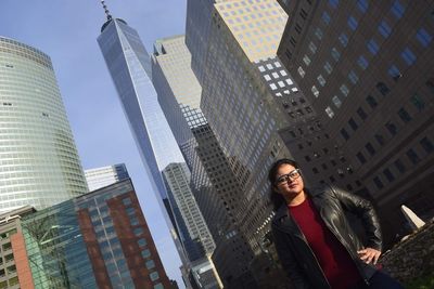 Low angle portrait of young woman standing against one world trade center