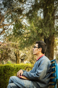 Side view of a young woman sitting on tree