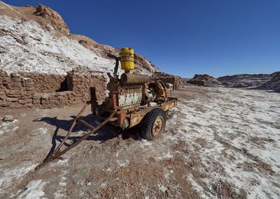 Abandoned vehicle on land against clear blue sky