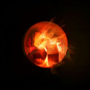 Close-up of burning candle against black background