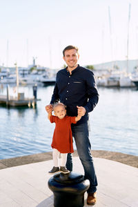 Portrait of smiling man standing on pier at harbor