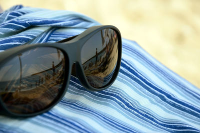 Reflection in sunglasses - silhouettes of people sunbathing by sea, beach umbrellas and lounge chair