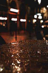 Close-up of wet glass on table in city at night