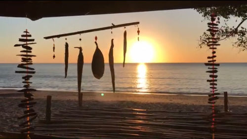 Silhouette wooden post in sea against sky during sunset