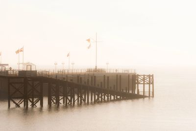 Pier on lake against clear sky in foggy weather