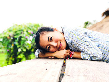 Portrait of young woman lying on wood