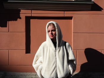 Young woman standing against wall