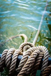 Close-up of rope tied to wooden post in sea