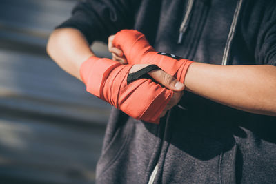 Midsection of man with arms outstretched standing outdoors