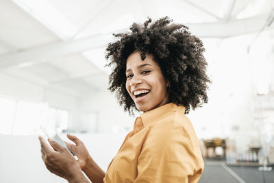 Portrait of happy young woman holding cell phone in office