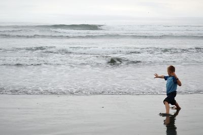 Full length of boy on beach against sky