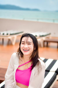 Portrait of young woman sitting on railing