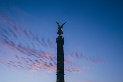 Low angle view of silhouette statue on column against sky during sunset