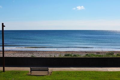 Bench by sea against sky