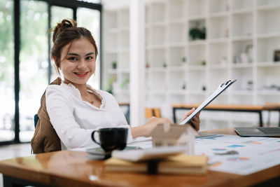 Portrait of young woman using mobile phone at table