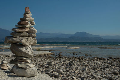 Stack of pebbles at beach against clear sky