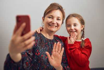 Mother with her little daughter making video call using mobile phone. keeping distance