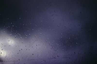 Low angle view of raindrops on glass window