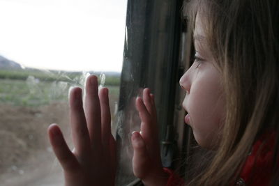 Close-up of girl looking through window