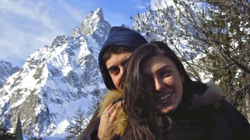 Portrait of smiling woman against snowcapped mountains during winter