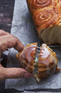 Cropped hand of woman picking cinnamon bun from wax paper