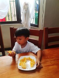 Boy sitting on table at home