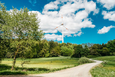 Road amidst trees on field against sky