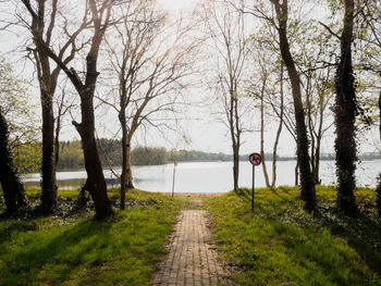 Footpath by lake against sky