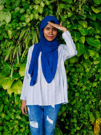 Portrait of smiling young woman standing against plants