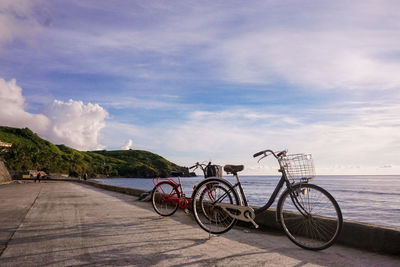 Bicycle on road by sea against sky