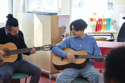 Teenagers attending guitar lesson