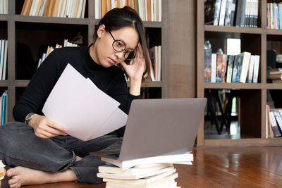 Young woman using laptop while sitting on sofa at home