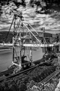 Cranes at harbor against sky