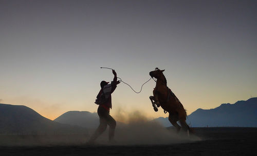 People on land against sky during sunset