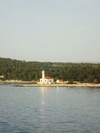 Lighthouse by sea against clear sky