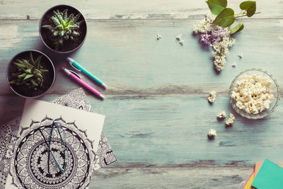 Directly above view of floral pattern on paper with popcorns and flowers over wooden table