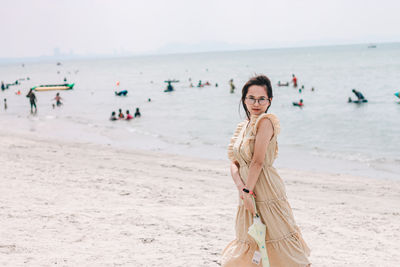 Portrait of woman standing at beach against sky