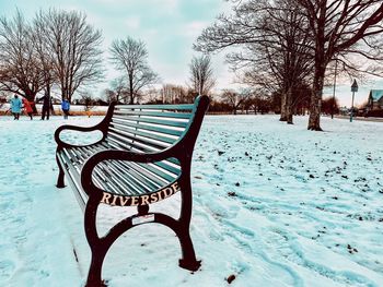 Empty bench in snow covered park