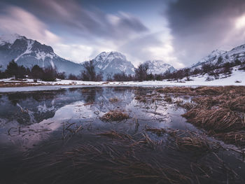 Scenic view of lake by snowcapped mountains against sky