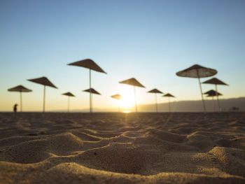 Umbrellas on beach against clear sky during sunset