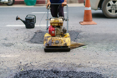 Road repair, workers and machinery are working paved road with asphalt and gravel