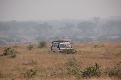 Abandoned car on field against sky