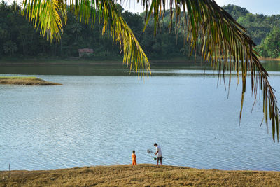 People on beach against palm trees