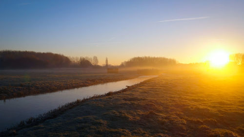 Scenic view of agricultural field against sky during sunset