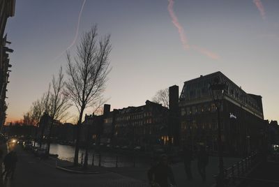 Silhouette people walking on road along buildings