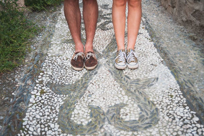 Low section of couple standing on mosaic footpath