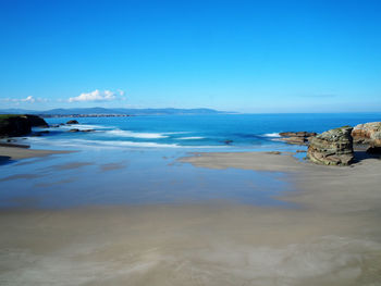 Scenic view of beach against blue sky