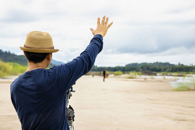 Rear view of man standing at beach against sky