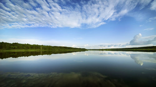 River landscape. green banks and white clouds are reflected in the mirror of the water.