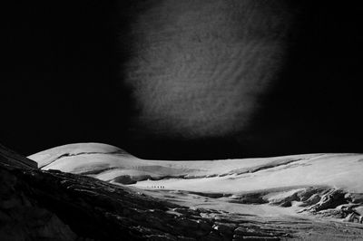 Snow covered landscape against sky at night